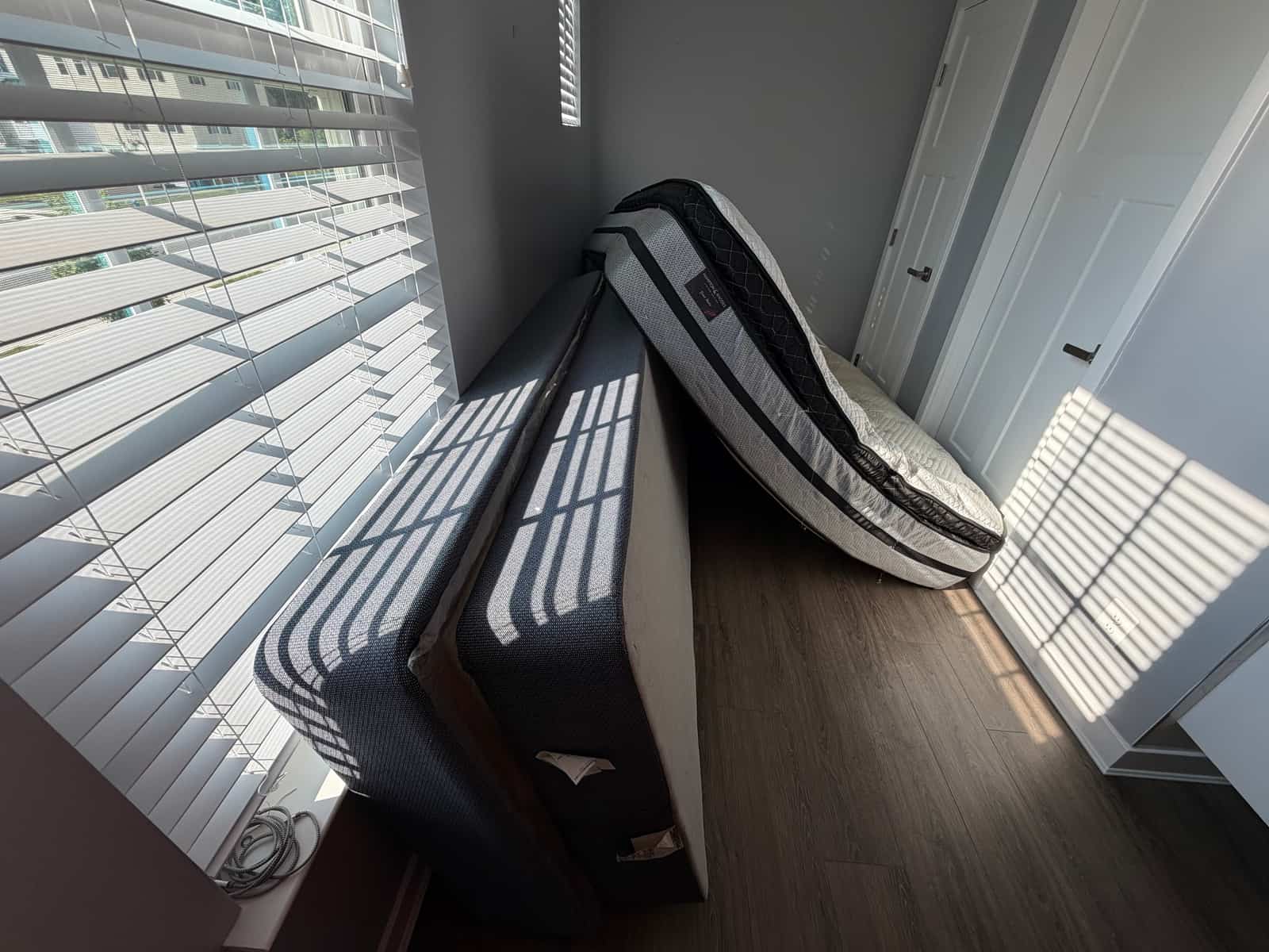 Mattresses and box springs stacked against the wall of a Delaware bedroom, ready for removal