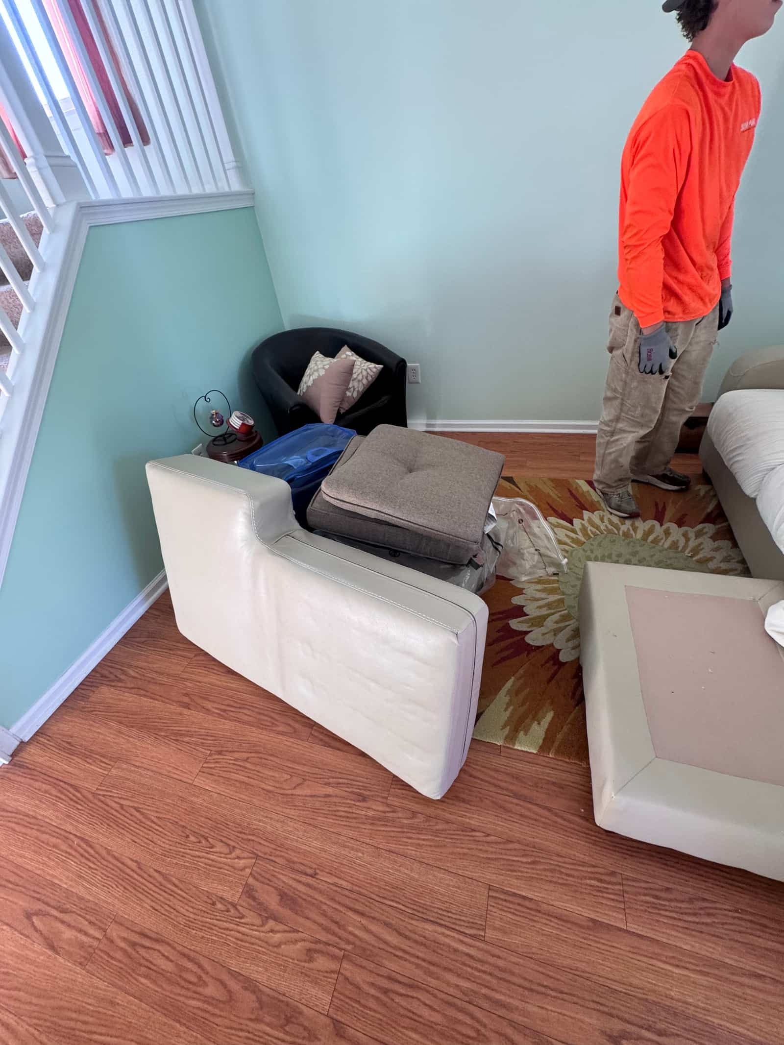 A Junk Away crew member breaking down a white leather sectional in a Middletown, DE living room