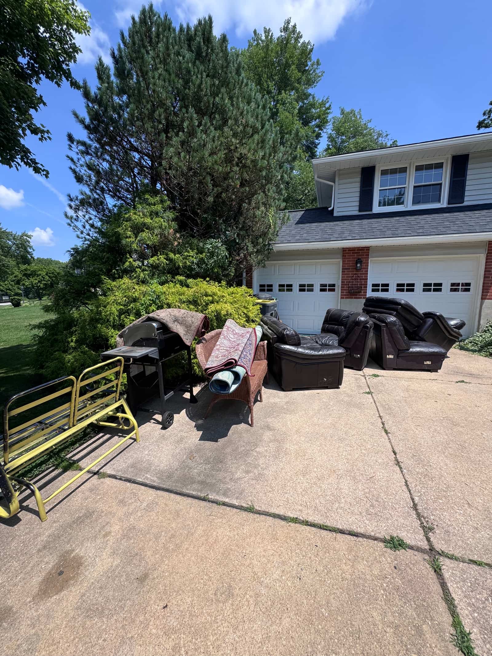 A Delaware driveway piled with leather recliners, a grill, rolled rugs and an old metal glider waiting for removal