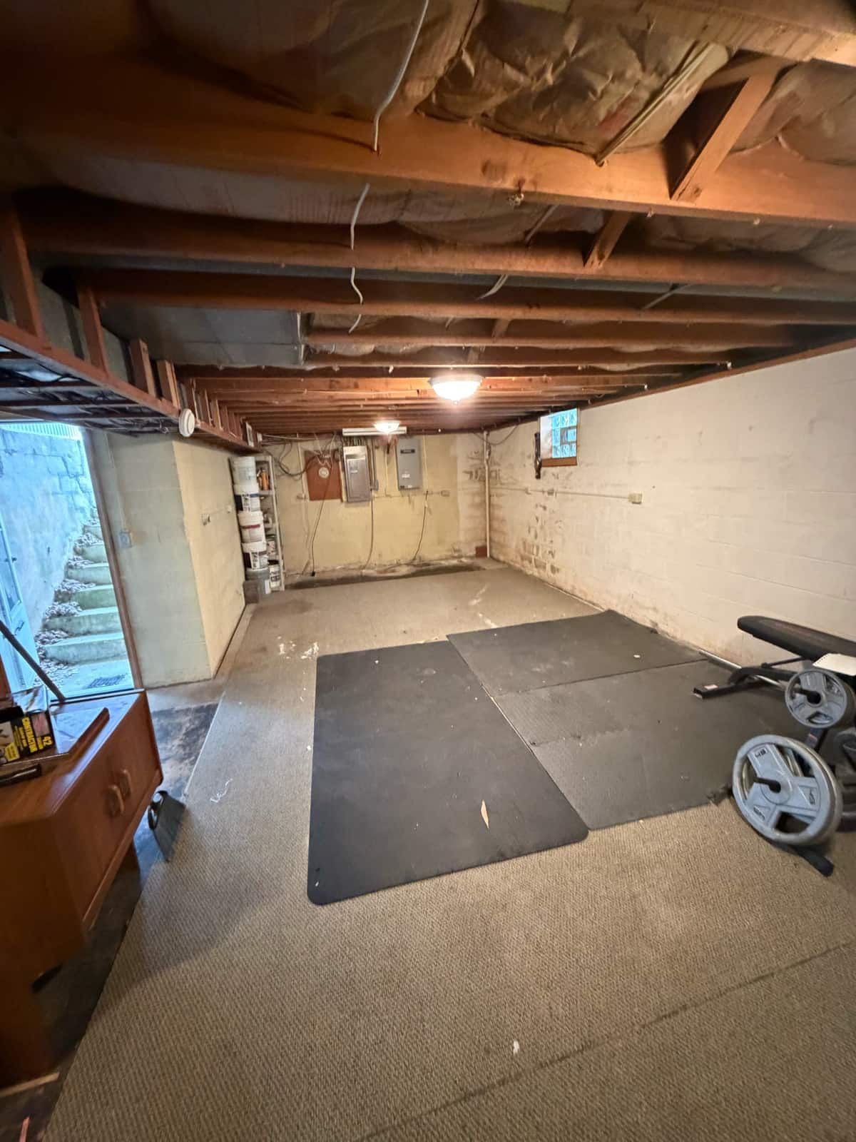 The same Wilmington basement cleared, with only the exercise mats and weight bench left in place