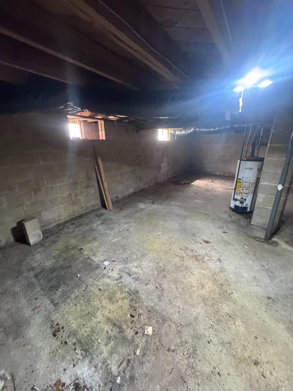 The same Smyrna basement cleared, with an empty concrete floor and the water heater left in place