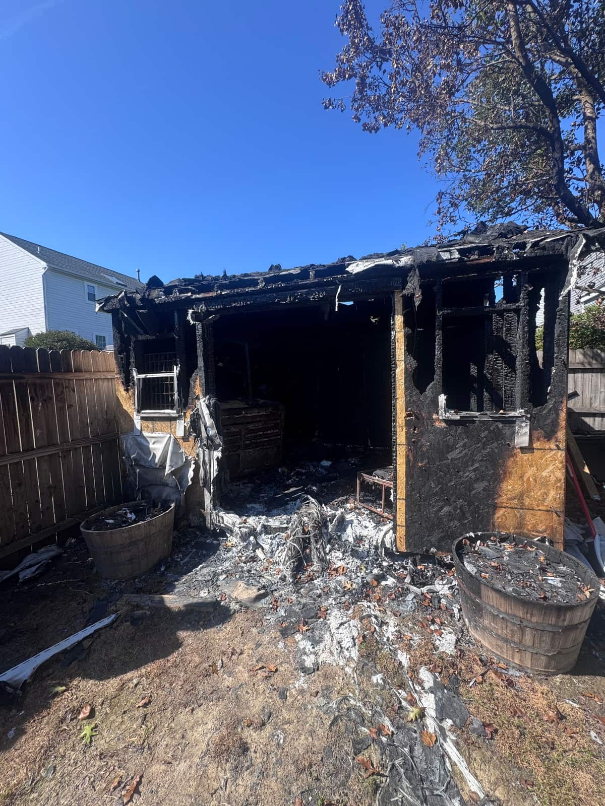 A Newark backyard shed burned down to its charred frame after a fire, with ash and debris across the ground