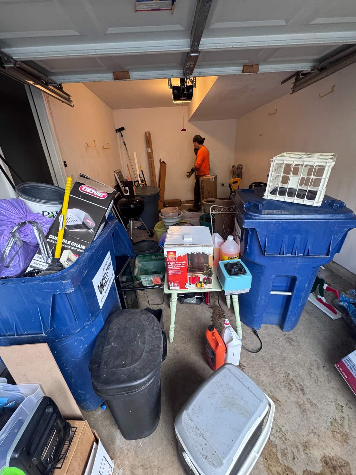 A Bear garage packed with carts, bins, tools and boxes before the cleanout, with a Junk Away crew member working at the back wall