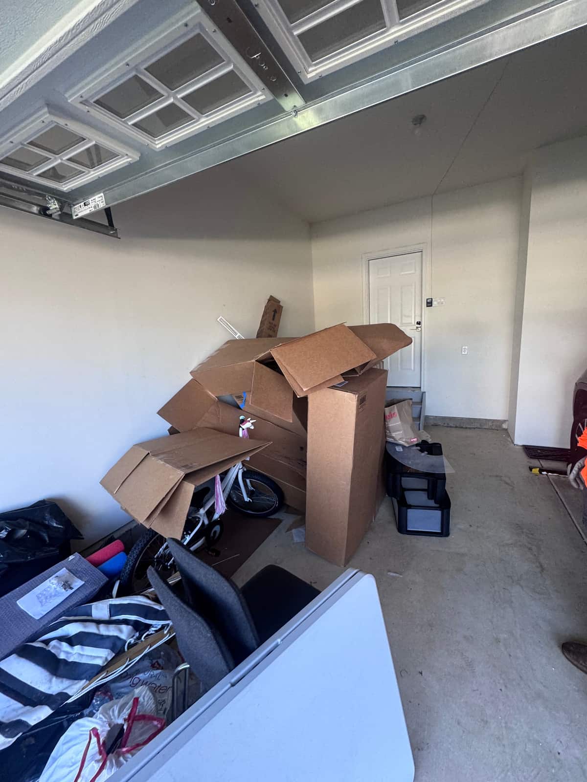 A Middletown garage with open moving boxes, a folding table, a child's bike and bagged items filling the floor before the cleanout