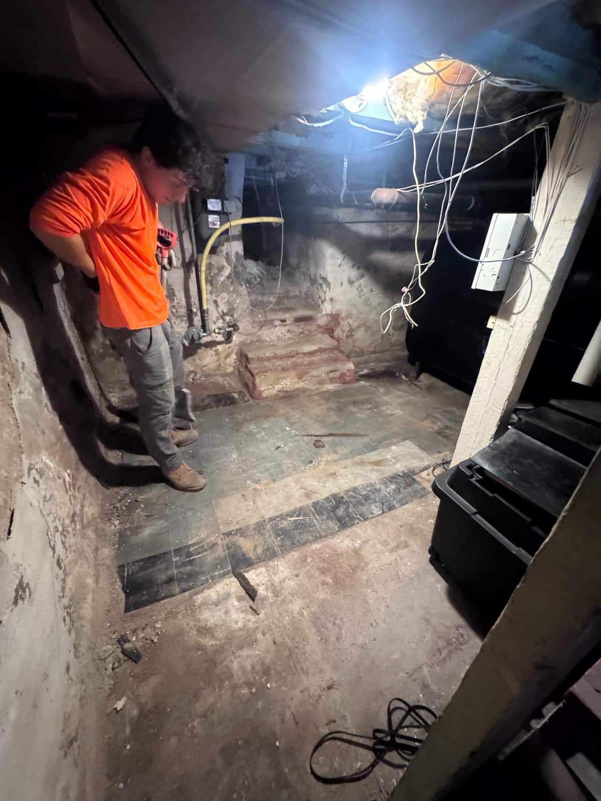 The same Wilmington basement cleared down to the old tile floor, with a Junk Away crew member checking the corner