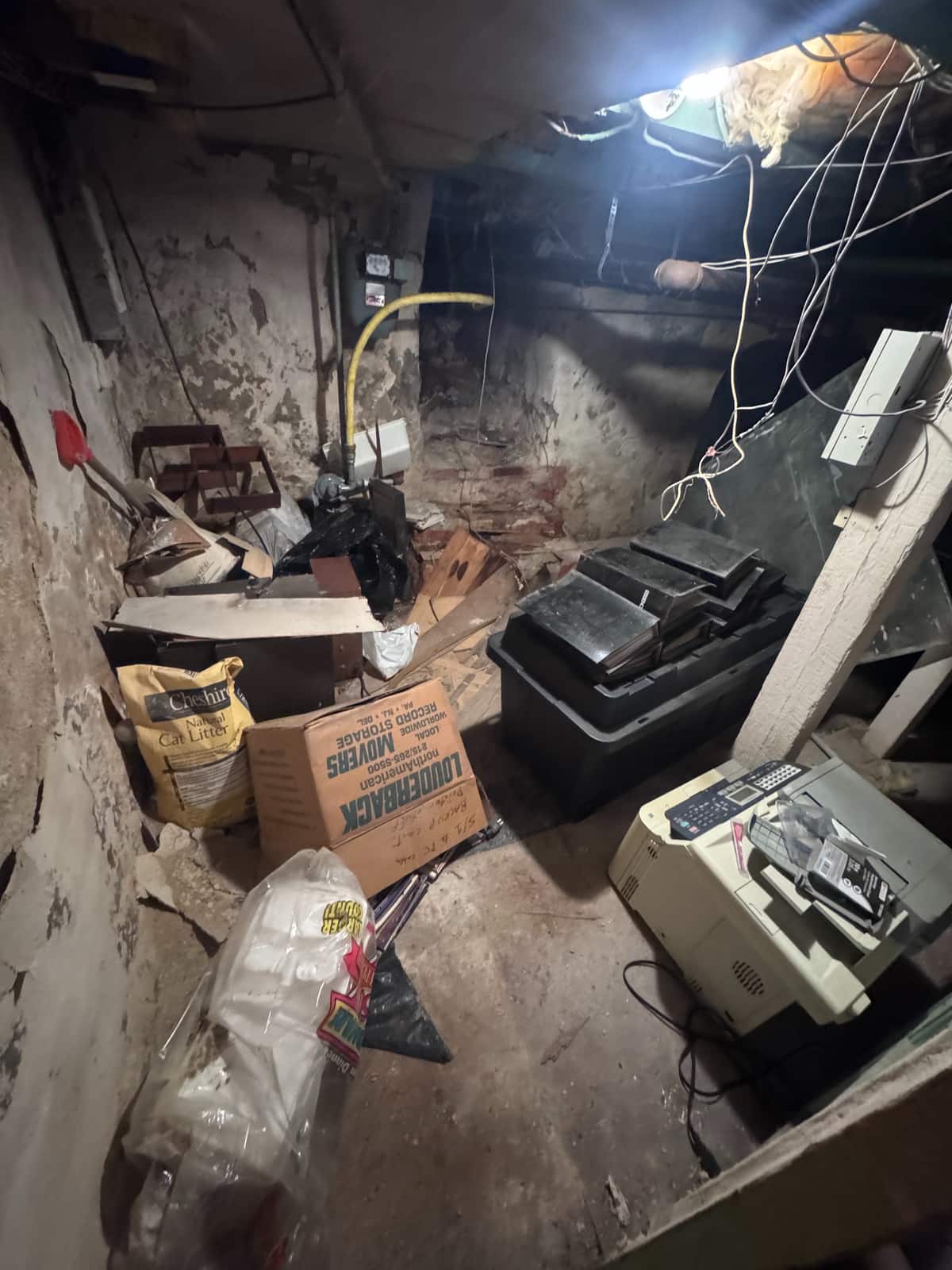 A low, stone-walled Wilmington basement crowded with boxes, bags, bins and an old printer before the cleanout